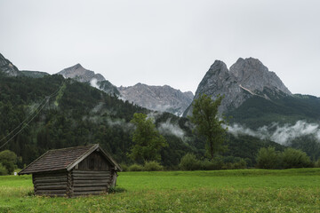 Fototapeta na wymiar The Mountains Alpspitze and Waxenstein in the morning after the rain with a hut in the foreground. 