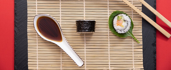 Présentation de plat de cuisine Japonaise, dés de saumon, sushi et maki sur fond noir avec baguettes.