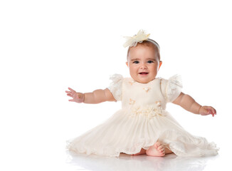 Little model baby in a smart dress and a bandage on her hair, sitting on the floor on a white background.