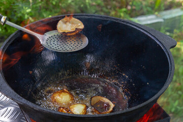 Cooking pilaf in a cauldron on the grill outside in the summer