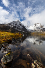 Fototapeta na wymiar Beautiful View of Scenic Alpine Lake, Rocks and Snowy Mountain Peaks in Canadian Nature. Season change from Fall to Winter. Taken at Grizzly Lake in Tombstone Territorial Park, Yukon, Canada.