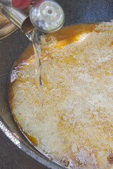 Cooking pilaf in a cauldron on the grill outside in the summer