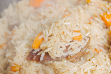 Cooking pilaf in a cauldron on the grill outside in the summer