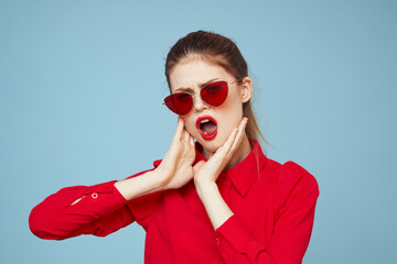 Beautiful woman in dark glasses red shirt bright makeup emotions attractive look blue background
