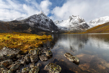 Beautiful View of Scenic Alpine Lake, Rocks and Snowy Mountain Peaks in Canadian Nature. Season change from Fall to Winter. Taken at Grizzly Lake in Tombstone Territorial Park, Yukon, Canada.