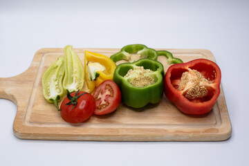 group of sweet peppers and tomatoes on a wooden cutting board, horizontal layout.