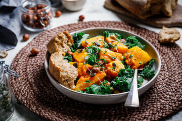 Season salad with grilled pumpkin, kale, chickpea, pepitas and nuts. Autumn vegetarian healthy recipe.