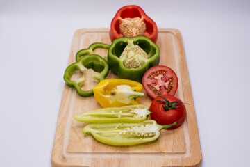 sweet peppers and tomatoes on a wooden cutting board, vertical layout.