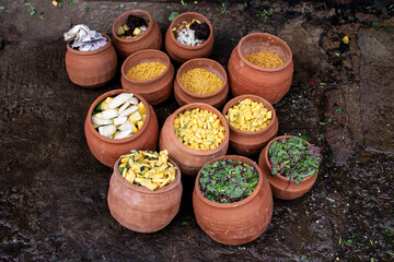 Vegetarian indian food in different clay pots on the stone floor