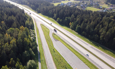 Top view of the long highway autobahn with cars through the forest