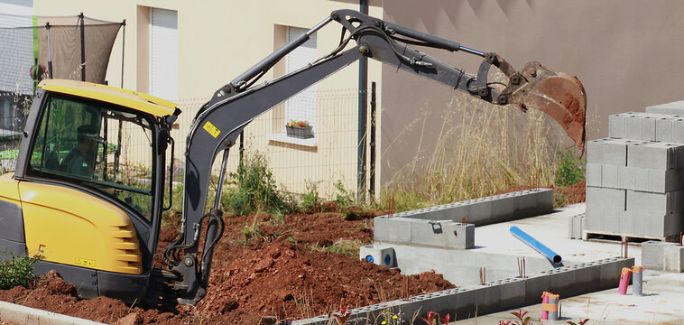 Travaux de terrassement avec une mini pelleteuse sur le chantier de construction d'une maison