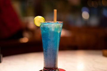 Cold and fresh blue cocktail in a seaside restaurant garnished with lemon peel and wooden straw in Bali