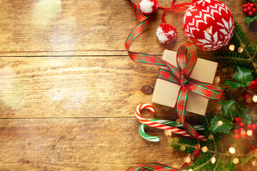 Christmas background with gift box, branches of holly and fir on  wooden background. Winter festive...