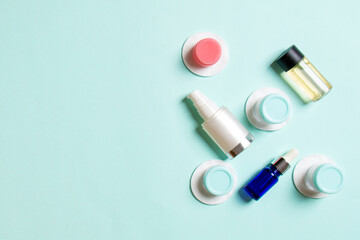 Set of travel size cosmetic bottles on colored background. Flat lay of cream jars. Top view of bodycare style concept