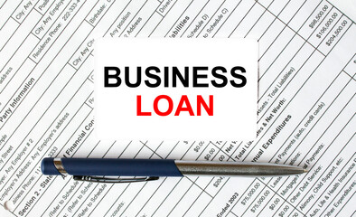 Text Business Loan written on a business card lying on financial tables with a blue metal pen