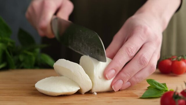 Female chef cutting fresh mozzarella cheese in slices