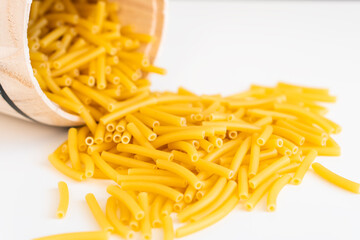 Raw dry uncooked Macaroni pasta spaghetti noodle on white bowl wooden background for basil tomato pesto sauce Homemade Italian food organic whole wheat vegan spaghetti for a healthy meal