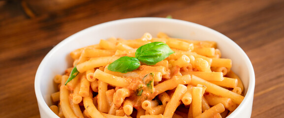 Healthy organic Italian macaroni homemade fresh pasta spaghetti noodles cook with basil tomato garlic pepper sauce with vegan vegetarian recipe in white bowl on wooden vintage table