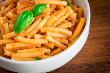 Healthy organic Italian macaroni homemade fresh pasta spaghetti noodles cook with basil tomato garlic pepper sauce with vegan vegetarian recipe in white bowl on wooden vintage table