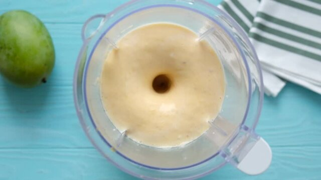Mango smoothie in a blender mixing in slow motion
