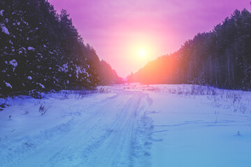Rural winter landscape at sunrise. Country road covered with snow