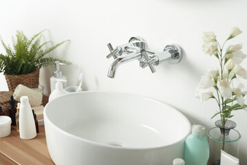 A light sink with a tap on a wooden countertop next to tubes of cream, face serums. Morning routine