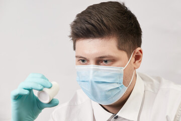 coronavirus concept, man in medical mask with capsules on white background