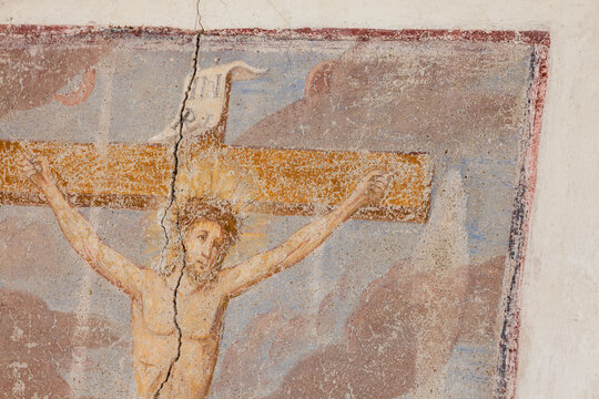 A detail of the Crucifixion painted on the external wall of an old residential building in the town of Selva in Val Gardena