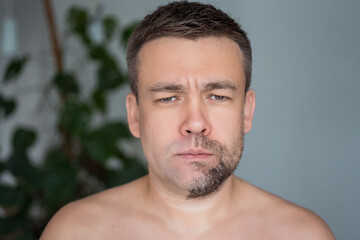 Obraz premium a sad man with stubble on one side of his face and shaved on the other. skin care concept. change of appearance.