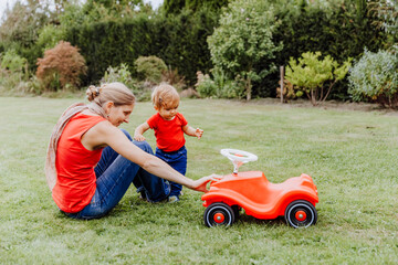 Mother and baby with toy car in garden
