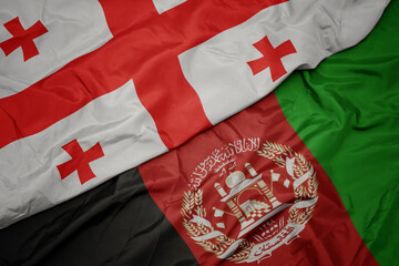 Fototapeta premium waving colorful flag of afghanistan and national flag of georgia. macro