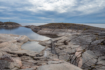 Fototapeta premium Russia. Karelia. Harsh Northern landscape. Rocky shore of lake Ladoga. nature of Russia. The hollows in the stones are filled with water. Karelia on a cloudy day. Travel to Russia.