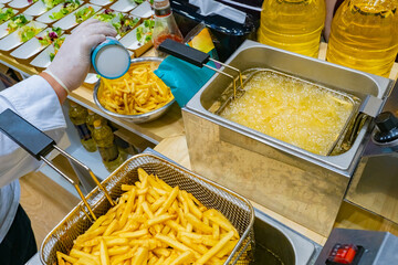 Preparation of potato dishes. Fast food restaurant. Industrial deep fryer. The cook is ready to...