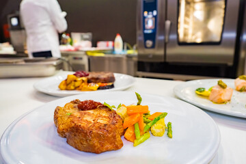 Plates with second courses on the table in the restaurant. Meat and fish dishes with side dishes. Cooking in the restaurant. Cook's job. Decoration of ready meals. Beautiful food decoration.