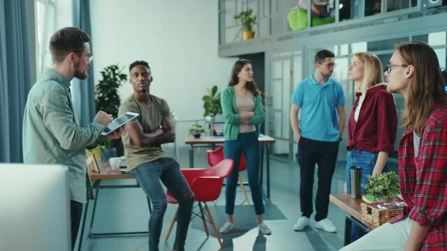 Bearded entrepreneur boss gathering his empoloyees to present recent robotic development. Automated cybernetic female robot new office worker. Successful start-up. Future.