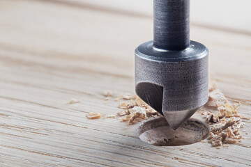 Countersink drill bit make sink in hole for screw in wooden plank.