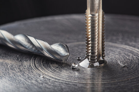 Thread tap drill steel billet with drill bit on background. Working cutter.
