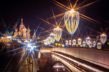 Fototapeta na wymiar Moscow. Russia. Festive lights of Moscow. Lights on the bridge are decorated with garlands. Glowing garlands on the background of St. Basil's Cathedral. Christmas in Moscow. New year's eve.