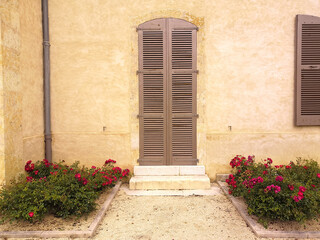 
Close-up of the closed wooden shutters of a beautiful stone building and its pretty little roses