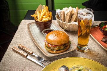 cheeseburger with french fries and glass of beer on the table at restaurant