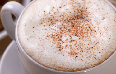 a white ceramic cup of cappucino as a coffee break concept