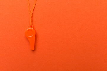 Orange sports whistle on orange background.Concept- sport competition, referee, statistics,...