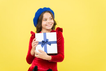 positive girl in vintage beret with gift box. trendy parisian child holding present. smiling teenager go shopping. seasonal sale and discounts. happy birthday. retro kid fashion style. copy space