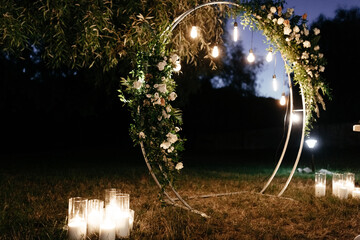 Circle wedding arch decorated with white flowers and lights in the evening. Wedding arch background