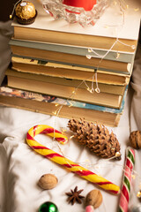 The atmosphere of Christmas and New Year. Big spruce cone, colorful candy, Christmas balls, walnuts and a stack of books