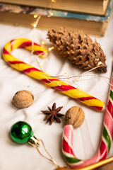 The atmosphere of Christmas and New Year. Big spruce cone, colored caramel paosokhs, Christmas balls and walnuts on a light background