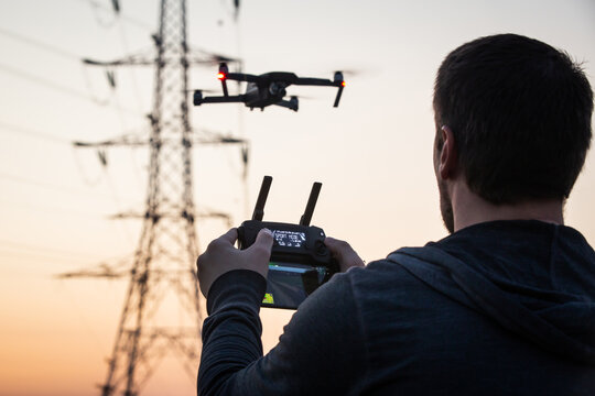 Man operating drone close to the electrical wire/ man holding remote control drones / drone controller. Drone safety.