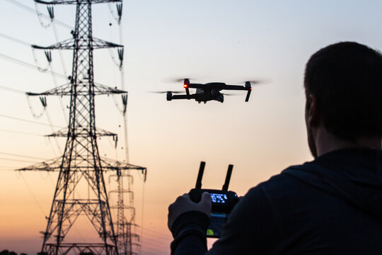 Man operating drone close to the electrical wire/ man holding remote control drones / drone controller. Drone safety.