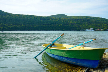 a fishing boat with oars stands on the water near the shore
