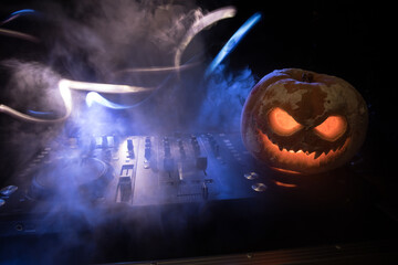 Halloween pumpkin on a dj table with headphones on dark background with copy space. Happy Halloween...